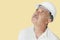 Senior construction worker with hardhat looking up over yellow background