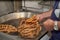 Senior cook removing churros from the boiling oil and placing them in a metal basket. Typical Spanish breakfast