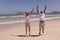 Senior couple with arms up jumping on beach