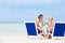 Senior Couple On Beach Relaxing In Chairs Drinking Champagne