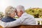 Senior couple, bonding and hug or relaxing together outdoors or romantic retirement and park bench. Elderly, partners