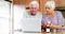 Senior couple checking medicine while using laptop in kitchen