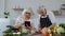 Senior couple cooking salad with vegetables. Woman dancing holding fresh slices of pepper on eyes