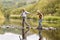 Senior Couple Crossing River Whilst Hiking In UK Lake District