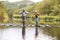 Senior Couple Crossing River Whilst Hiking In UK Lake District