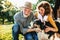 A senior couple crouching and petting a dog.