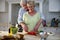 Senior couple cutting vegetables in kitchen