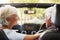 Senior Couple Drive Open Top Car On Countryside Road Trip