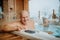 Senior couple enjoying together outdoor bathtub at their terrace during cold winter day.