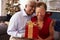 Senior Couple Exchanging Christmas Gifts At Home