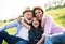 Senior couple with granddaughter outside in spring nature, relaxing on the grass.