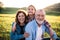 Senior couple with granddaughter outside in spring nature, relaxing on the grass.