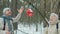 Senior couple hanging bird house on tree branch and talking enjoying walk in winter park