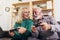 Senior couple having fun at home playing video game holding joysticks in hands.