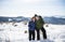 Senior couple hikers with nordic walking poles in snow-covered winter nature.