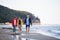 Senior couple holding hands with their preteen granddaughter and walking on sandy beach.