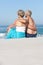 Senior Couple On Holiday Sitting On Sandy Beach