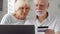 Senior couple at home. Shopping online with credit card on laptop. Active modern life after retirement