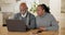 Senior couple, laptop and talk in home with smile for reading, typing and check email notification. Elderly African man