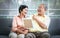 Senior couple looking at a photo frame and laughing at each other while sitting on a couch, for family conection concept