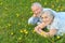 Senior couple lying on green meadow with dandelions