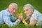 Senior couple lying on green meadow with dandelions