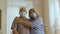 Senior couple in medical mask standing at home and hugging