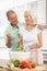 Senior Couple Preparing Salad In Kitchen