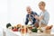 Senior couple recording video about vegetarian food on camera in kitchen