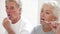 Senior Couple Reflected In Bathroom Mirror Brushing Teeth