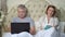 Senior couple relaxing in bed with laptop and book