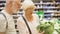 Senior couple shopping in grocery store. Standing in vegetable department choosing fresh salad