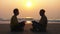 Senior couple sits and meditating together on sandy beach