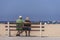 Senior couple sitting on boardwalk bench, Santa Monica, CA, USA
