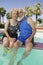 Senior Couple sitting on edge of swimming pool portrait.