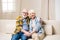 Senior couple sitting embracing on sofa and smiling at camera