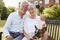 Senior Couple Sitting On Garden Bench With Pet French Bulldog