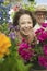 Senior Couple sitting in plant nursery seen through bed of flowers portrait