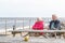 Senior couple sitting on the seaside table bench looking over the Southwold beach