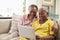 Senior Couple Sitting On Sofa Using Laptop At Home Together