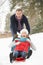 Senior Couple Sledging Through Snowy Woodland