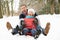 Senior Couple Sledging Through Snowy Woodland