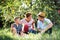 A senior couple with small grandson in apple orchard eating apples.