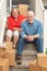 Senior Couple On Stairs Surrounded By Moving Boxes