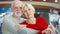 Senior couple stand in mall look at camera. Loving hugging pensioners in shopping center smiling