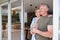 Senior Couple Standing And Looking Out Of Kitchen Door Drinking Coffee