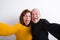 Senior couple sticking tongues out, taking selfie. Studio shot.