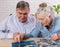 A senior couple in their 80s , searching for the pieces of the jigsaw puzzle they`re assembling at home