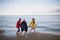 Senior couple and their preteen granddaughter running and having fun on sandy beach.