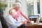 Senior Couple Using Laptop On Desk At Home